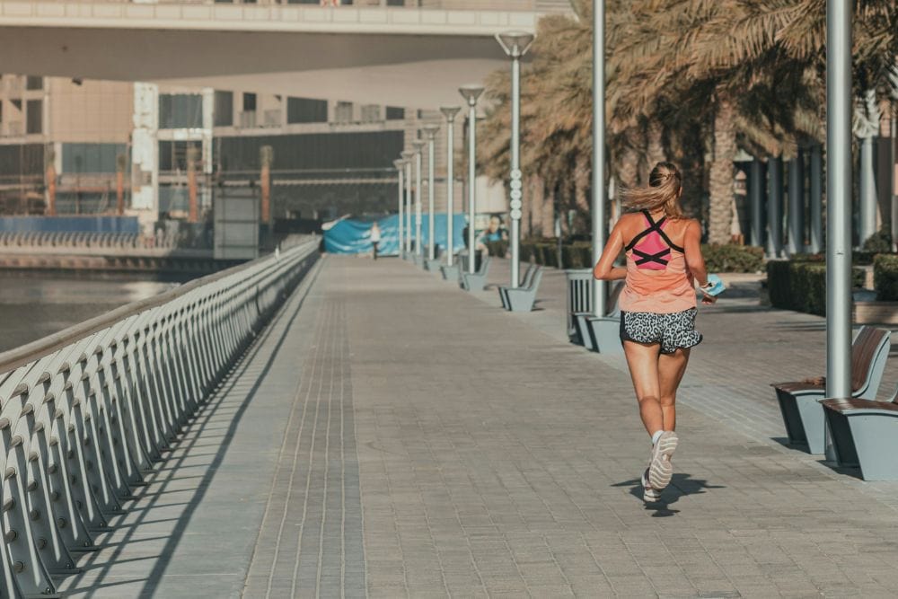Titelbild Kalorienverbrauch beim Joggen - Frau joggt an Promenade